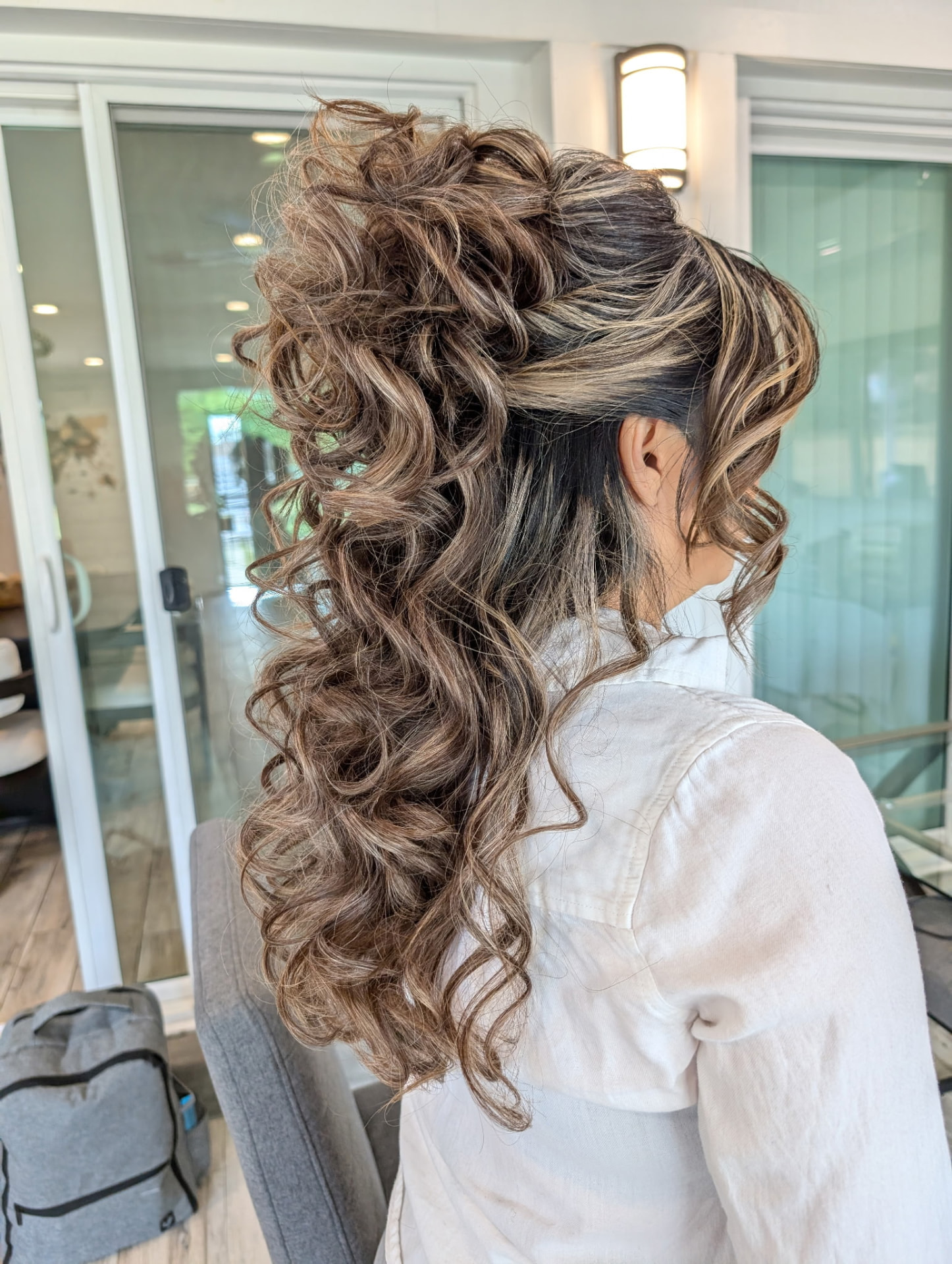Long curled half-up style with blonde highlights by Hair By Sess