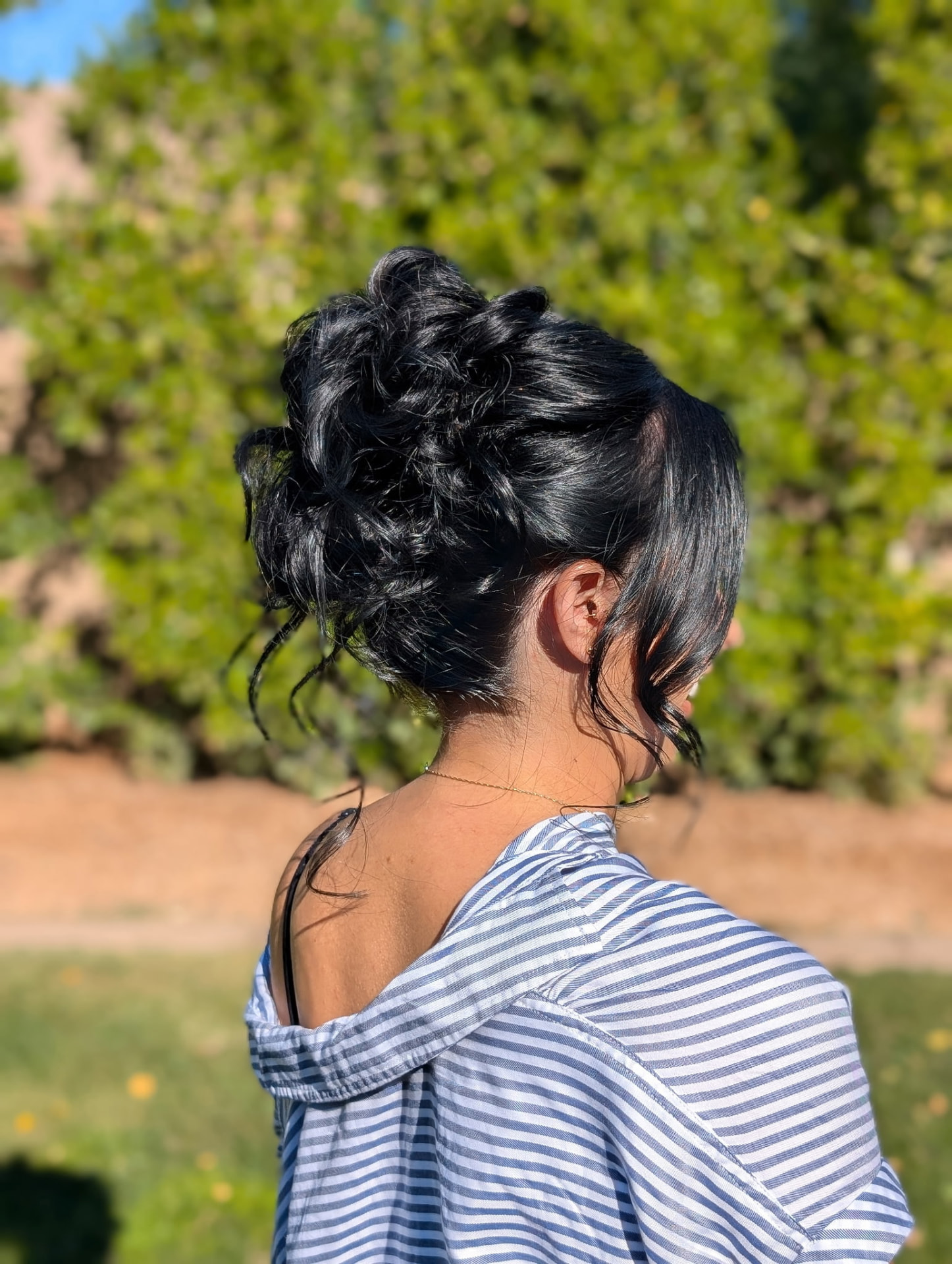 Textured curly high updo with face-framing pieces by Hair By Sess